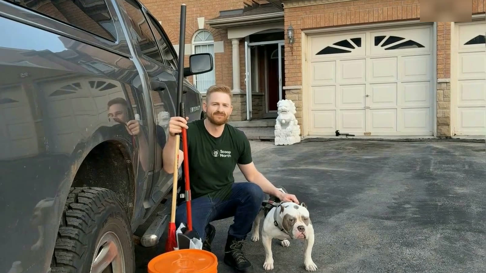 A Scoop North technician crouched with a dog beside the truck outside a Maple home