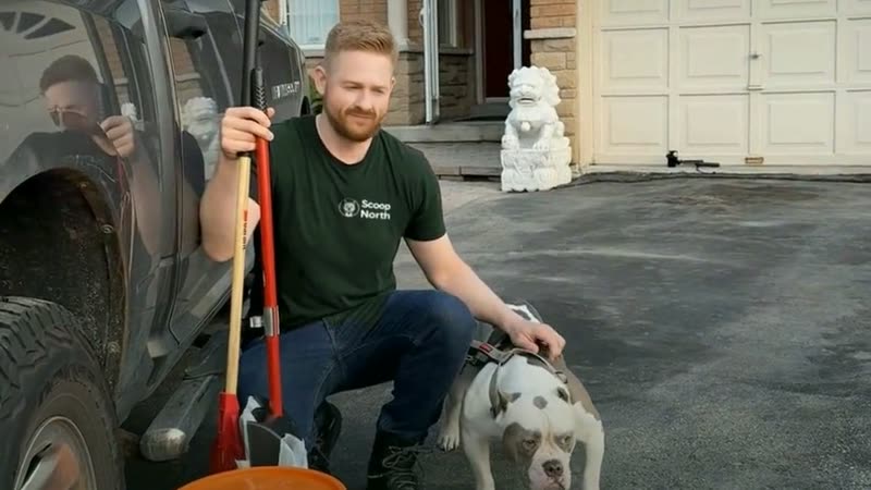 A Scoop North technician crouched with a dog beside the service truck